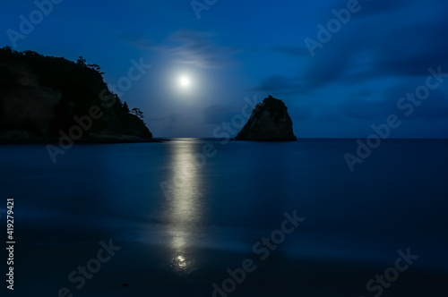 Beautiful moon setting on the horizon  reflecting on the sea and an islet composing the beautiful scenery. Iriomote Island.