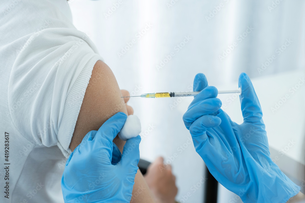 The doctor's hand holding a syringe and was about to vaccinate a patient in the clinic to prevent the spread of the virus The doctor's hand holding a syringe and was about to vaccinate a patient in the clinic to prevent the spread of the virus