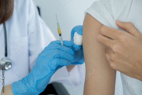 The doctor's hand holding a syringe and was about to vaccinate a patient in the clinic to prevent the spread of the virus