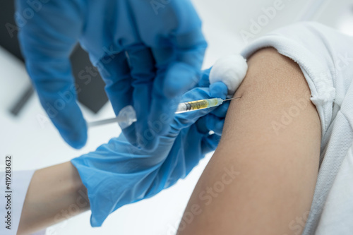 The doctor s hand holding a syringe and was about to vaccinate a patient in the clinic to prevent the spread of the virus