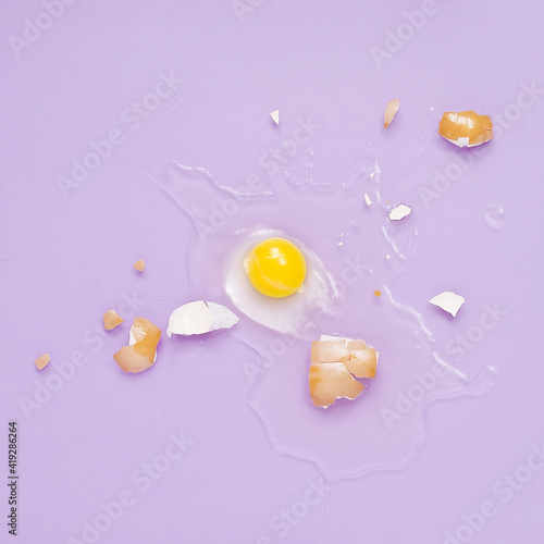 Cracked egg, eggshell with yolk isolated on purple background. Broken idea concept.