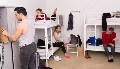 Tableau sur toile Man traveler staying in comfy hostel, putting his belongings in locker