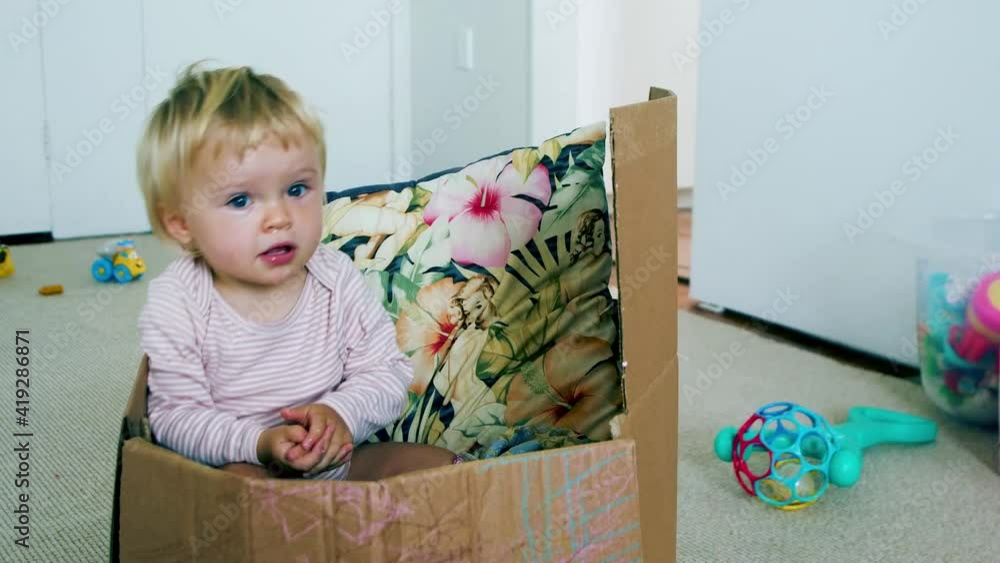 Small Toddler sitting inside a cardboard boxing filled with pillows, rocking back and forward Small Toddler sitting inside a cardboard boxing filled with pillows, rocking back and forward