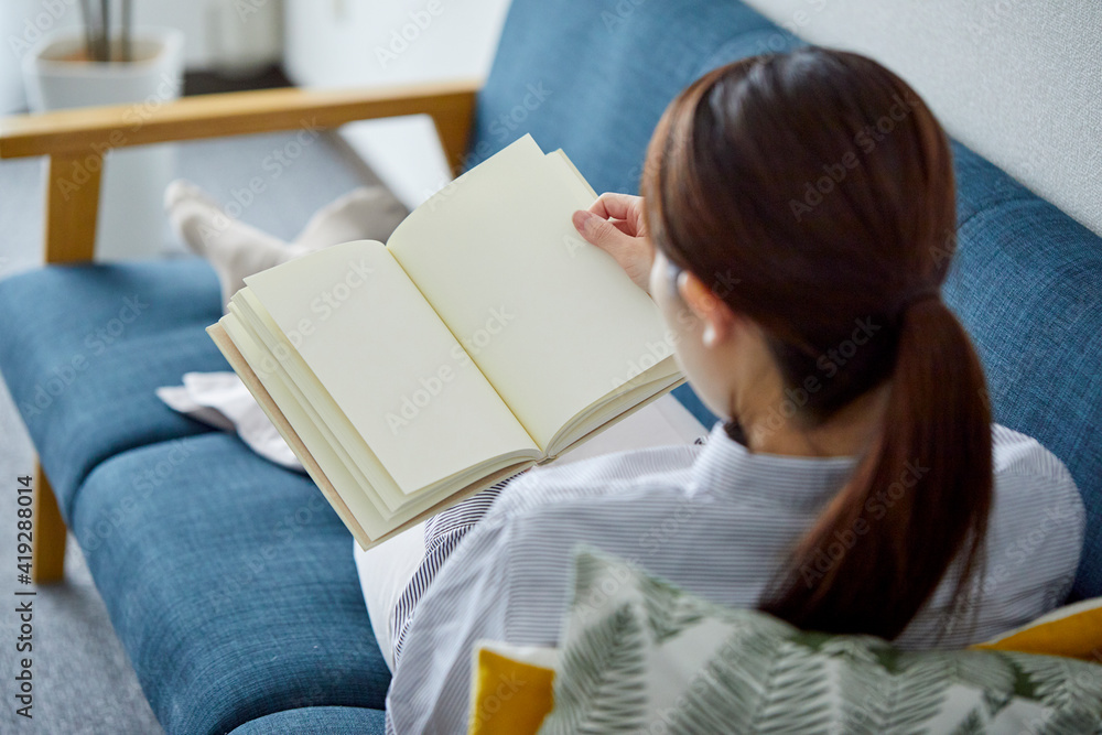 リビングでリラックスして本を読む女性 リビングでリラックスして本を読む女性