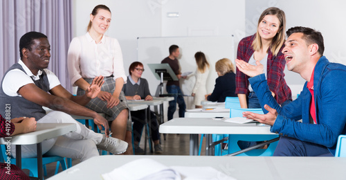 Positive adult students communicating during recess between lectures in auditorium