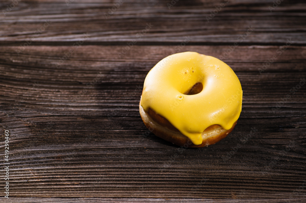 bright yellow donut with banana filling on a wooden table, top view, place for text