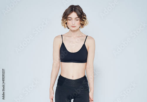 A slender woman with a short haircut goes in for sports on a light background