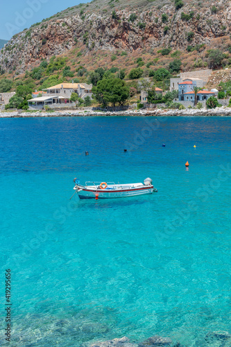 view of Limeni village with fishing boats in turquoise waters and the stone buildings as a background in Mani, South Peloponnese , Greece.