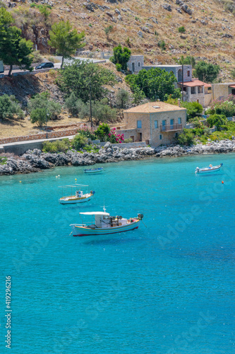 view of Limeni village with fishing boats in turquoise waters and the stone buildings as a background in Mani, South Peloponnese , Greece.