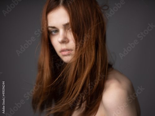 Beautiful red-haired woman on gray background cropped view naked shoulders close-up model