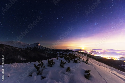 Night winter landscapes in the High Tatras, with mountain houses on a background of snow-capped mountains and starry sky