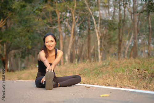 Young woman runner stretching legs before outdoor workout.