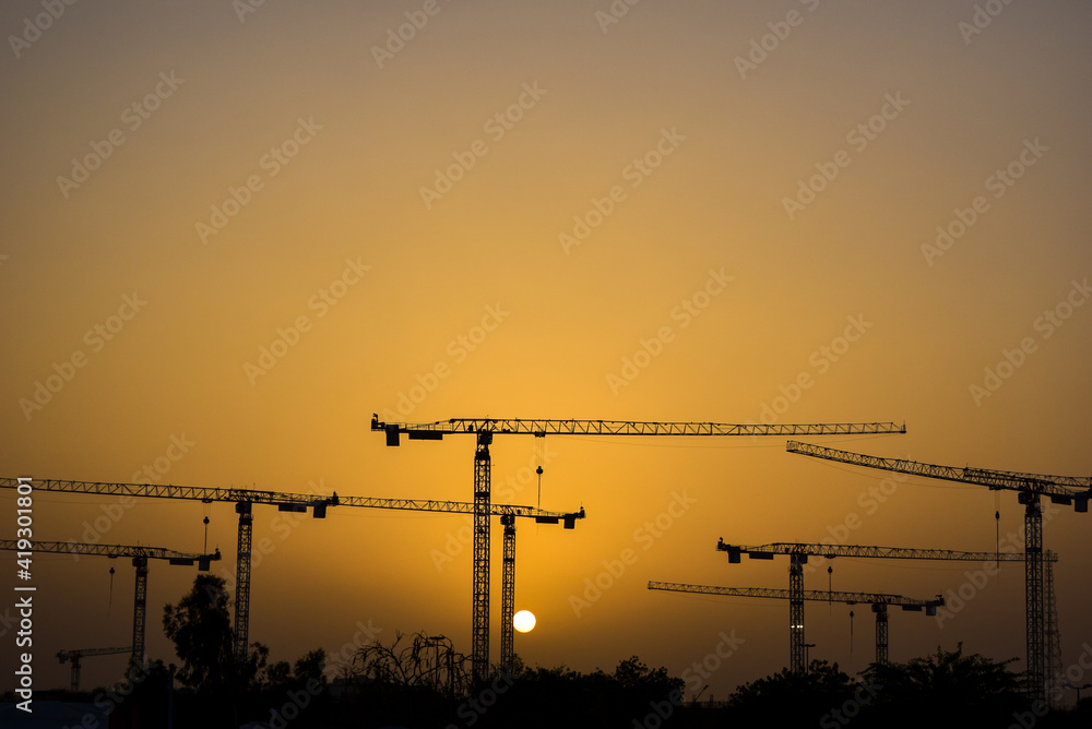 Sunset over cranes in construction site Sunset over cranes in construction site