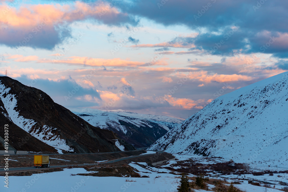 Panorama of a beautiful landscape with high mountains in winter. Field, road and forest near the snowy mountains in Turkey.