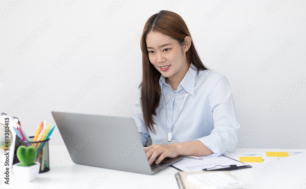 Young Asian office worker presses her finger on a laptop keyboard to analyze financial data and summarize her work in a private office, Office workers, beautiful female employee wearing a blue shirt. Young Asian office worker presses her finger on a laptop keyboard to analyze financial data and summarize her work in a private office, Office workers, beautiful female employee wearing a blue shirt.
