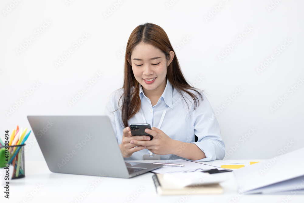 Asian female employees are analyzing market data via smartphones and have laptops to calculate the company's finances In a private office at home, Working at home and new normal concept. Asian female employees are analyzing market data via smartphones and have laptops to calculate the company's finances In a private office at home, Working at home and new normal concept.