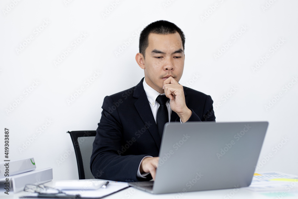 Young Asian office worker presses he finger on a laptop keyboard to analyze financial data and summarize her work in a private office, Office workers, handsome male employee in a black suit. Young Asian office worker presses he finger on a laptop keyboard to analyze financial data and summarize her work in a private office, Office workers, handsome male employee in a black suit.