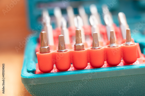 Drill bit kit, close up. 1-inch steel square driver bits in foreground. The kit is blue green with red driver sets. Beautiful defocused and abstract varieties of driver bit sets. Selective focus. photo