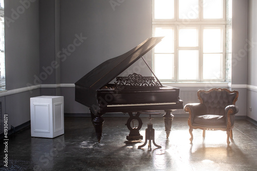 black antique grand piano in the interior with beautiful light from the window