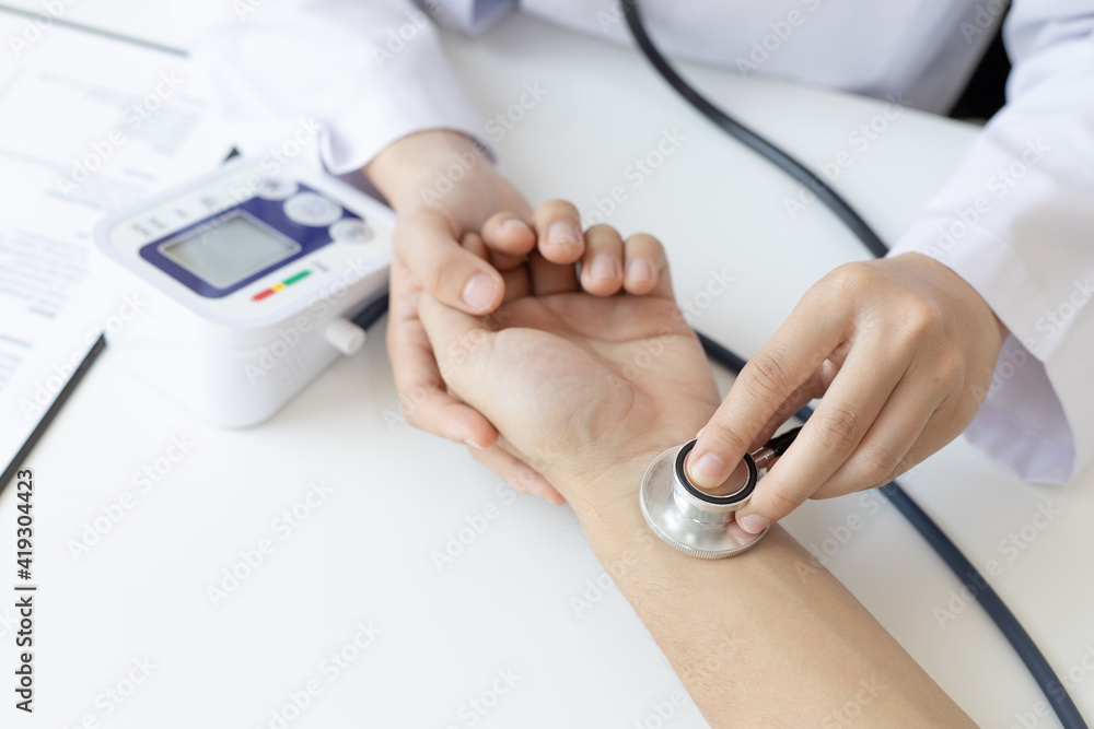 Female doctor uses a heart rate monitor of a male patient to take an initial pulse, Early health examination at a clinic or hospital. Female doctor uses a heart rate monitor of a male patient to take an initial pulse, Early health examination at a clinic or hospital.