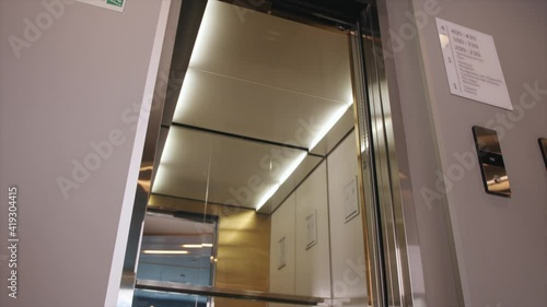 Black businessman walking to elevator and pushing lift button down on panel in apartment corridor. Close up black man entering into elevator car and door closing