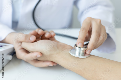 Female doctor uses a heart rate monitor of a male patient to take an initial pulse, Early health examination at a clinic or hospital.