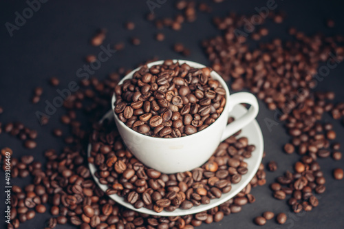 coffee beans In a saucer and in a cup of coffee on a gray background female hand macro photography