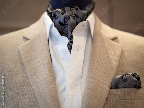 Tableau sur toile Close up of beige jacket suit with white shirt and ascot tie scarf on mannequin