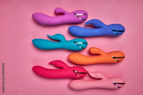 Discover sexier you. Collection of different colorful G-spot vibrators arranged on pink background. Smart gadget and masturbation device. View from above. Place for text. Flat lay. Sex shop concept. photo