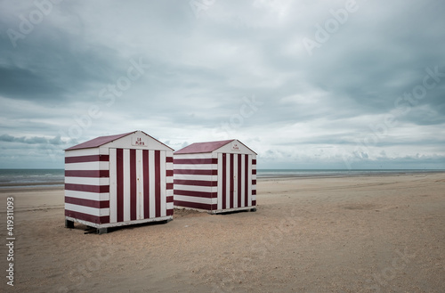 Two vintage beach cabins against grey sky