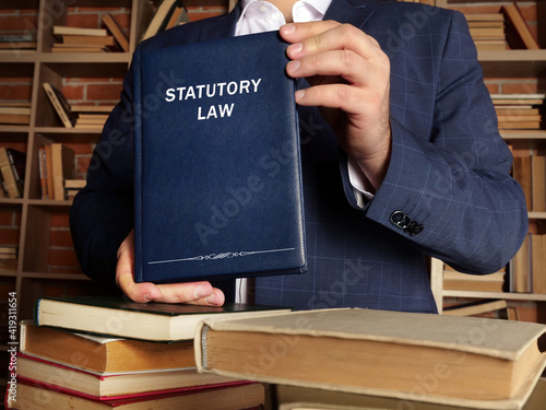 Lawyer holds STATUTORY LAW book. Statutory law or statute law is written law passed by a body of legislature