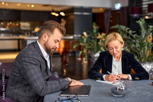 woman translator writes down all the business strategies coming out of the mouth of a smart confident businessman, in restaurant