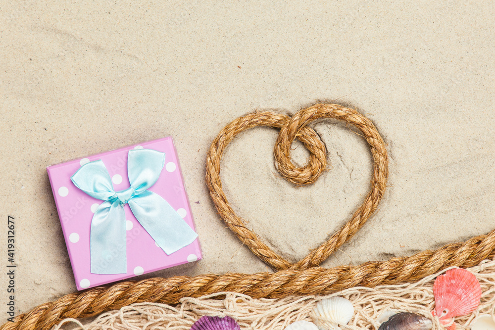 Gift box and rope in heart shape near net and shells Gift box and rope in heart shape near net and shells