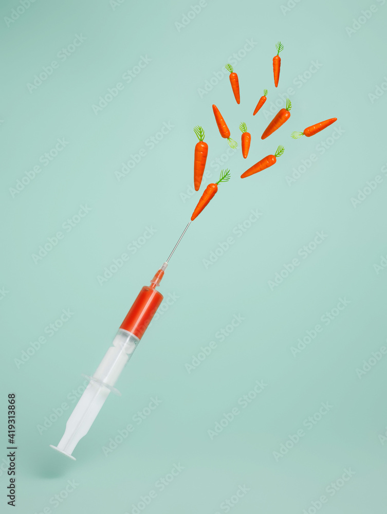 Spray of carrots coming out syringe on pastel green background. Minimal Easter celebration concept. Creative vaccination or coronavirus layout. Spray of carrots coming out syringe on pastel green background. Minimal Easter celebration concept. Creative vaccination or coronavirus layout.