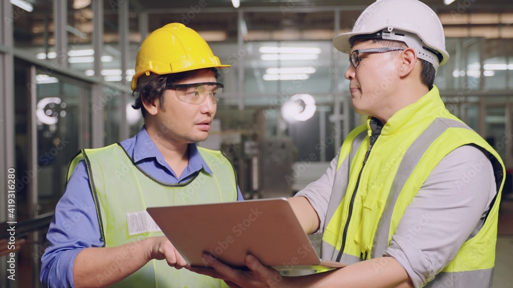 Asian manager feeling upset with the engine machine of the factory arguing about planning procedure of work, he scolding industrial workers for low level of quality standing in factory workshop Asian manager feeling upset with the engine machine of the factory arguing about planning procedure of work, he scolding industrial workers for low level of quality standing in factory workshop