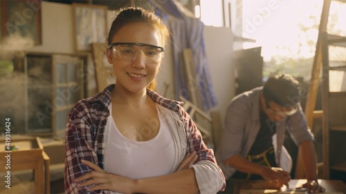 Asian woman carpenter standing and smiling in home workshop. Teenage female is high experience and skill professional work at home. concept of business and work from home. photo