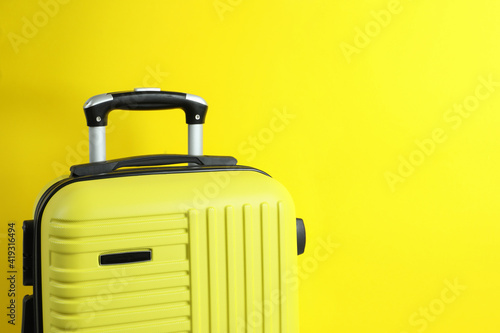 Travel bag on yellow background, space for text