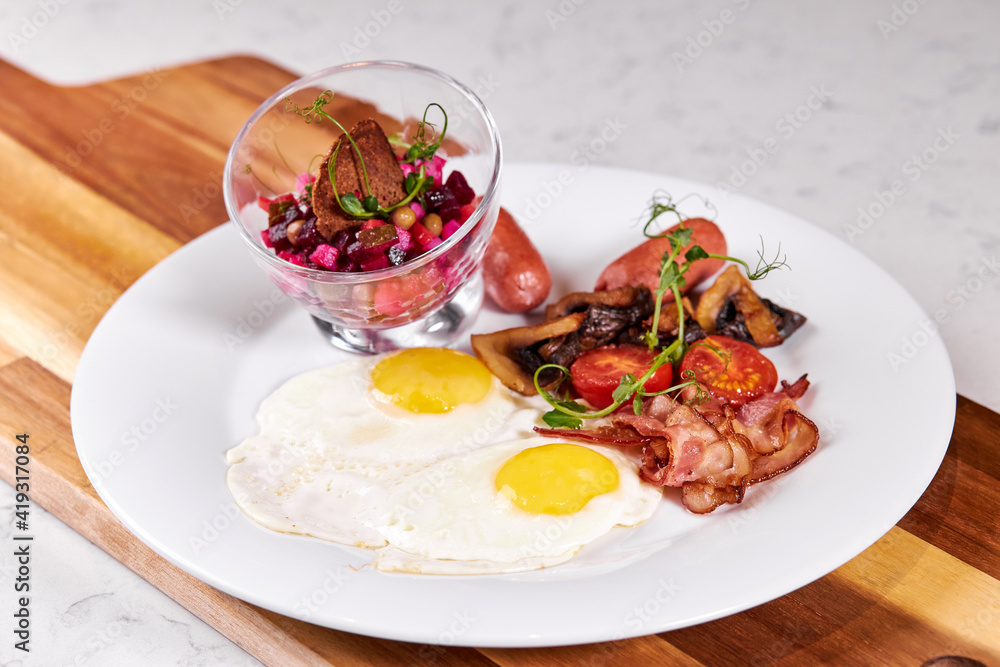 Prettily Decorated Dish On Plate, Fried Eggs Bacon, Tomato and Salad Served At Table, Flat Lay Close-up photo. Menu, Cooking, Food, Restaurant concept Prettily Decorated Dish On Plate, Fried Eggs Bacon, Tomato and Salad Served At Table, Flat Lay Close-up photo. Menu, Cooking, Food, Restaurant concept