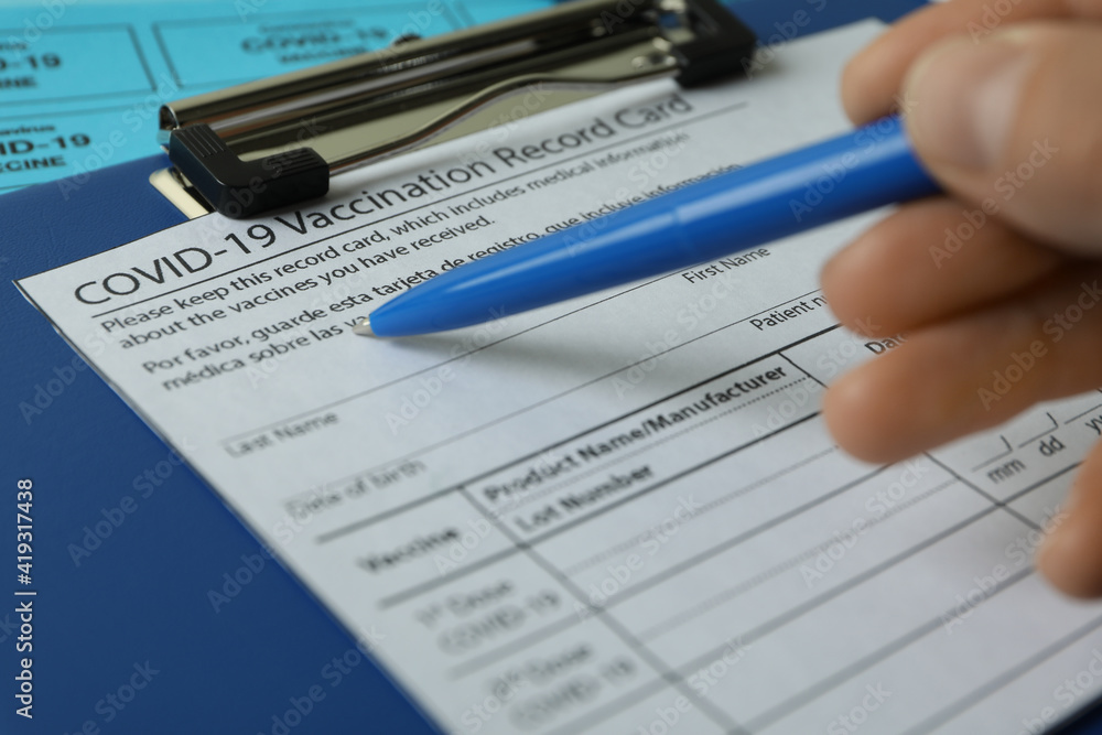 Female hand holds pen on Vaccination record card, close up Female hand holds pen on Vaccination record card, close up