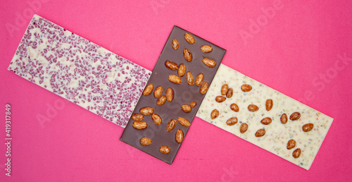 a lot of different, sweet, delicate chocolate bars on pink background photo taken from above