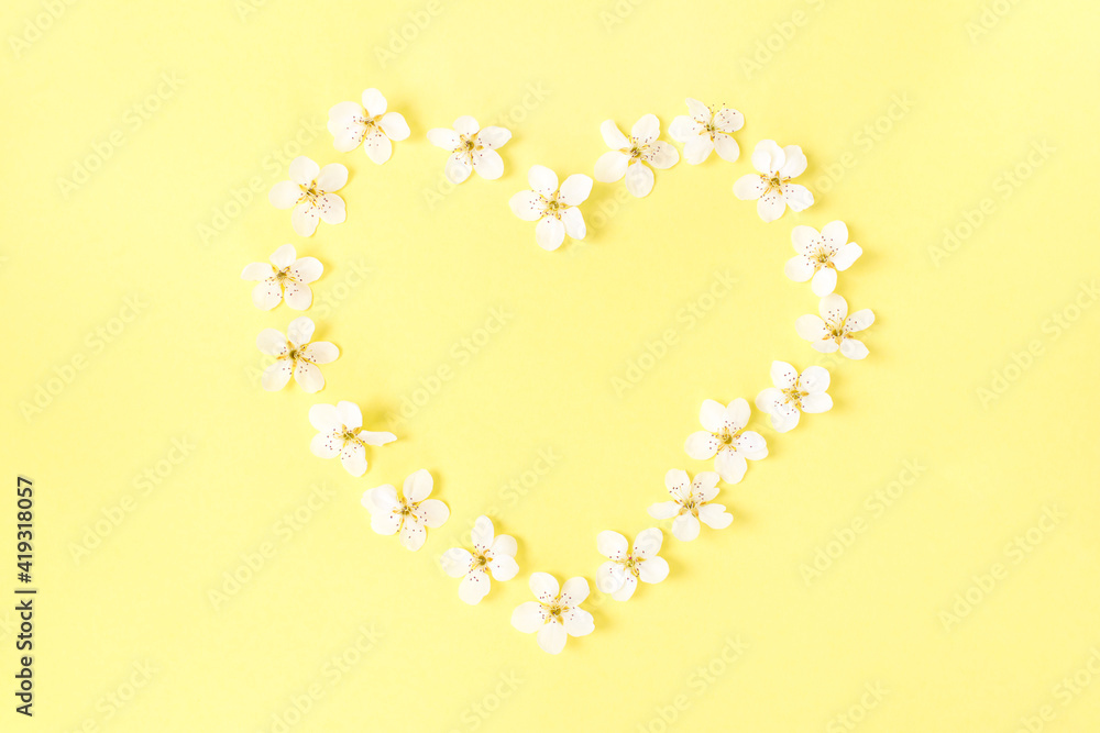 Heart of spring or summer flowers on a yellow background. Flowers composition. Copy space for your text. Flat lay style. Top view. Heart of spring or summer flowers on a yellow background. Flowers composition. Copy space for your text. Flat lay style. Top view.
