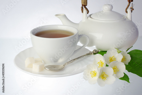 Fototapeta Naklejka Na Ścianę i Meble -  White faience tea cup, teapot and jasmine flowers.