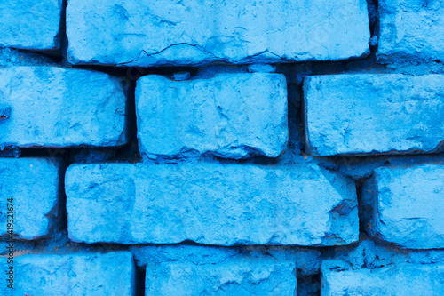 Blue paint brick wall background. Urban rustic closeup texture. Antique house exterior wall. Vintage abandoned building architecture. Destroyed and cracked brick construction.