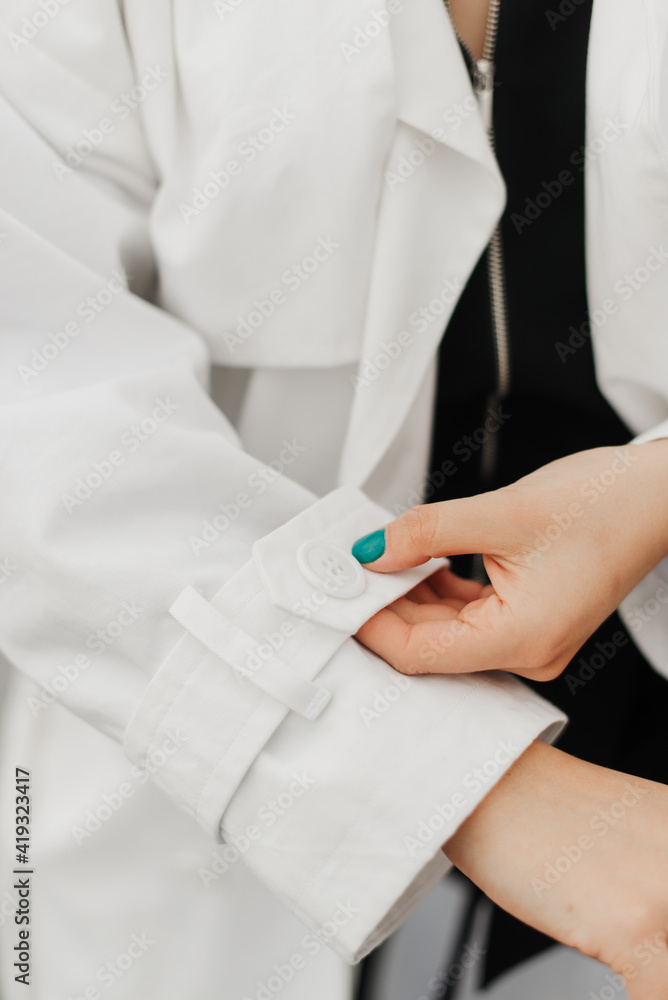 the girl straightens the sleeve of her white coat the girl straightens the sleeve of her white coat