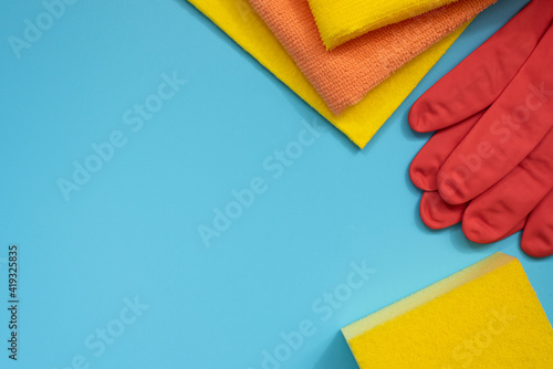 Obraz na płótnie House cleaning supplies: sponge, rubber gloves and cloths on blue background. Top view. Copy space. w salonie