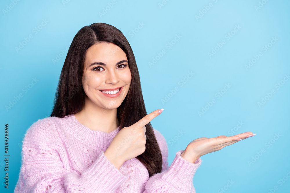 Photo of young woman happy positive smile indicate finger product offer promo ad advice choice isolated over blue color background Photo of young woman happy positive smile indicate finger product offer promo ad advice choice isolated over blue color background