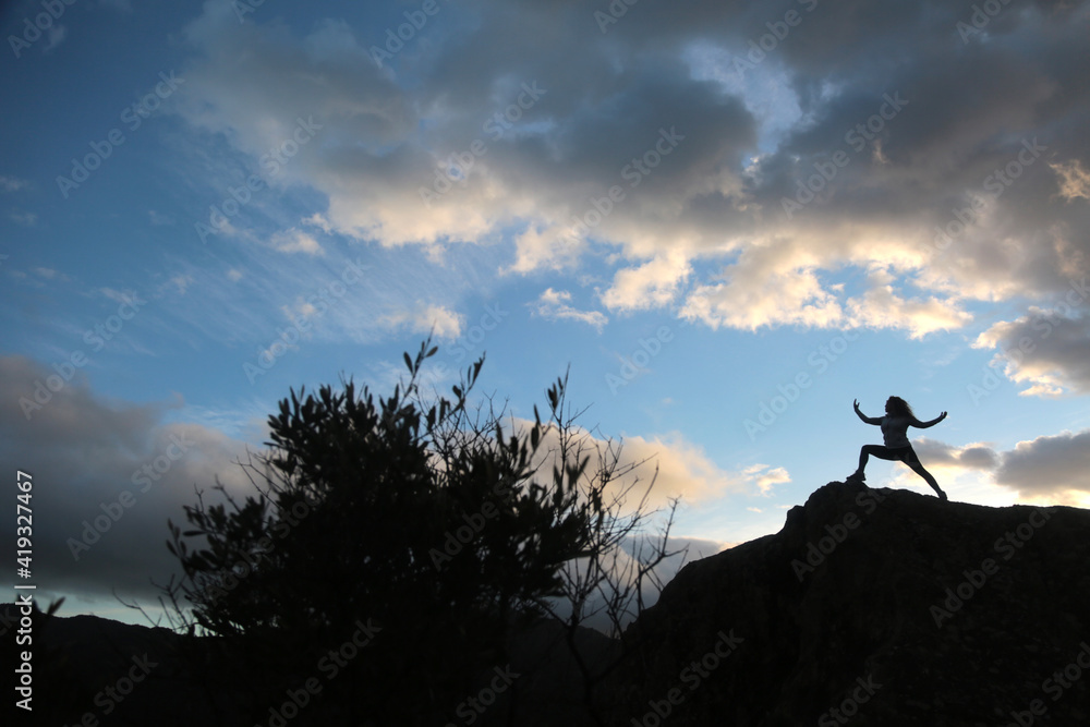 woman meditating outdoors in the mountain with sky and clouds background