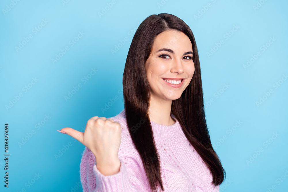 Photo of young cheerful girl happy positive smile point thumb empty space select suggest advise ad isolated over blue color background Photo of young cheerful girl happy positive smile point thumb empty space select suggest advise ad isolated over blue color background