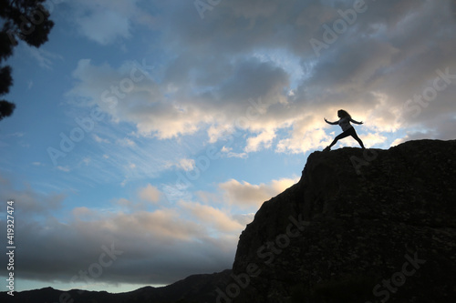 woman meditating outdoors in the mountain with sky and clouds background