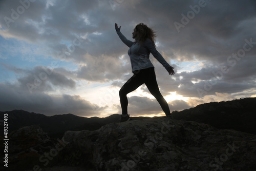 woman meditating outdoors in the mountain with sky and clouds background